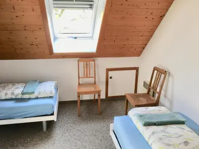 a bedroom with two beds and a window and two chairs at Sitter-Panorama in Bischofszell
