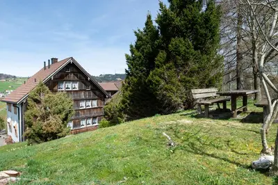 a house on a hill with a bench in front of it at Ferienhotel Idyll Gais in Gais