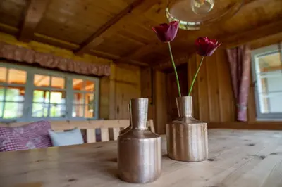 two metal vases sitting on a wooden table with roses at Ferienhotel Idyll Gais in Gais