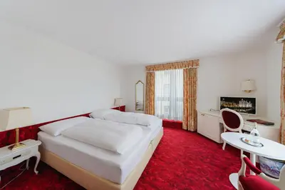 a bedroom with a white bed and a red carpet at Hotel Mozart in Rorschach