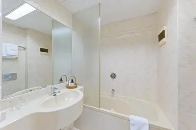 a white bathroom with a tub and a sink at Hotel Mozart in Rorschach