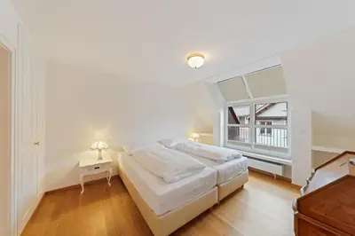 a white bedroom with a large bed and a window at Hotel Mozart in Rorschach
