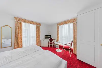 a bedroom with a white bed and a table and chairs at Hotel Mozart in Rorschach