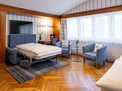 a bedroom with a bed and two chairs and a television at Hotel Hecht in Appenzell