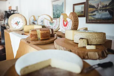 a bunch of different types of cheese on cutting boards at Hotel Hirschen Wildhaus in Wildhaus