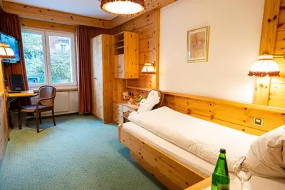 a bedroom with a bed and a desk and a table at Hotel Sonne in Wildhaus