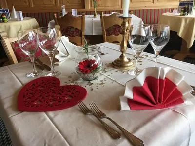 a table with a red heart on a table with wine glasses at Hotel Sonne in Wildhaus