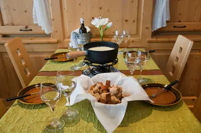 a table with a plate of food and wine glasses at Hotel Sonne in Wildhaus