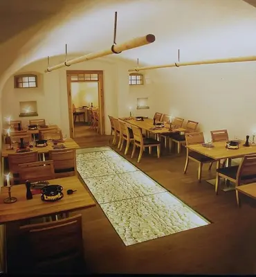 a large room with wooden tables and chairs and a rug at Adler Hotel in Appenzell