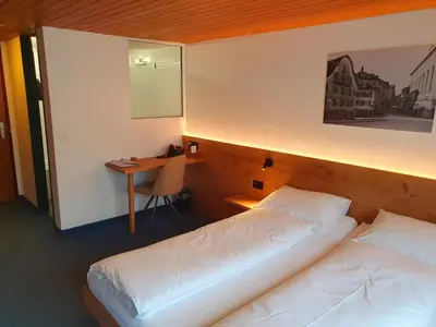 a hotel room with two beds and a desk at Adler Hotel in Appenzell