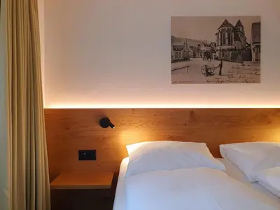 a bed with white sheets and a picture on the wall at Adler Hotel in Appenzell