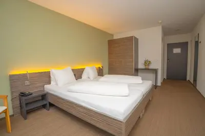 a bedroom with a large bed with white sheets at Hotel Restaurant Seegarten in Arbon