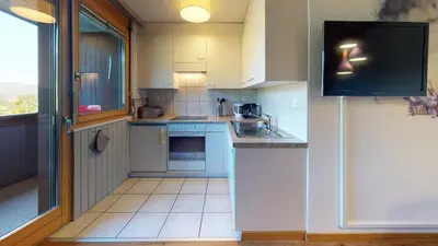 a kitchen with blue appliances and a large window at Reka-Feriendorf Wildhaus in Wildhaus