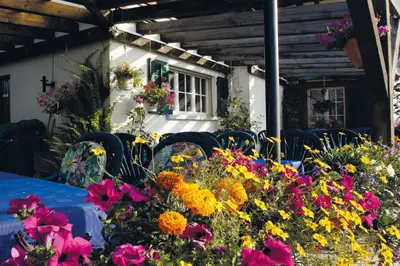 a table with chairs and flowers in front of a building at Hotel Garni Sonne in Landschlacht Gemeinde Münsterlingen