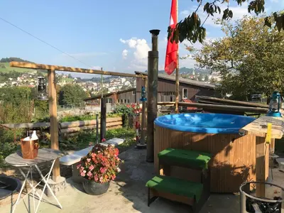 a hot tub in a yard with a table and chairs at Hof Dietrich in Herisau