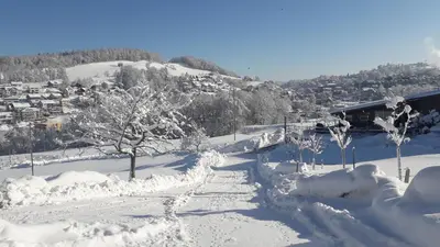 a snow covered slope with trees and a city at Hof Dietrich in Herisau