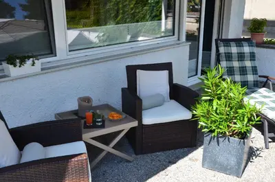 a patio with two chairs and a table and a window at Lakelodge Romanshorn in Romanshorn