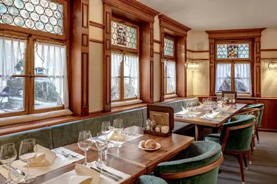 a restaurant with wooden tables and chairs and windows at Hotel Appenzell in Appenzell
