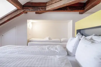 two white beds in a bedroom with wooden ceilings at Linde Heiden Swiss Quality Hotel in Heiden