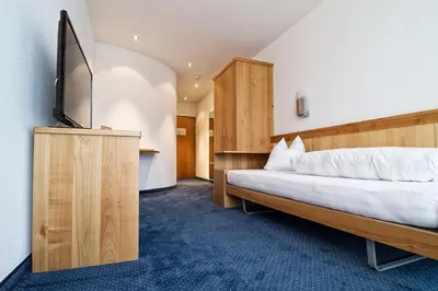 a bedroom with a bed and a flat screen tv at Hotel Rössli Tufertschwil in Lütisburg