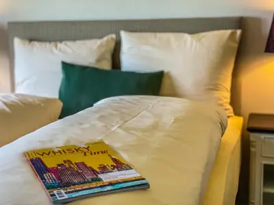 a bed with a book on it with pillows at Trompeterschlössle Hotel & Residence in Tägerwilen
