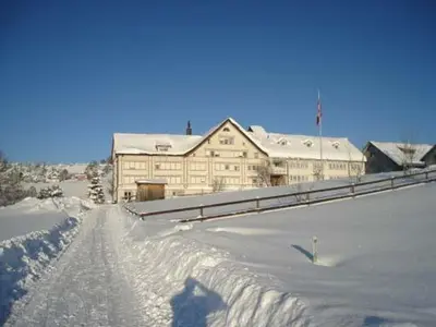 a snow covered road in front of a large building at Hotel am Schönenbühl in Speicher