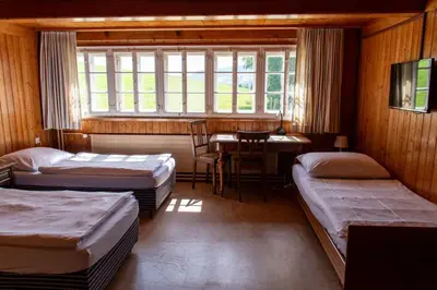 a room with three beds and a table and a window at Hotel am Schönenbühl in Speicher