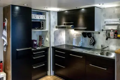 a kitchen with black cabinets and a sink and a refrigerator at Ferienwohnungen im Fürstenland in Gossau