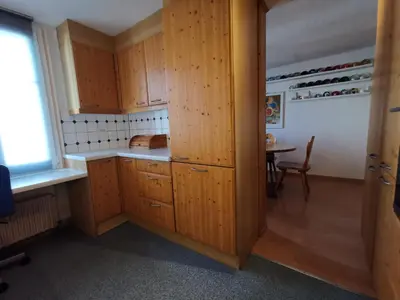 a kitchen with wooden cabinets and a table with a window at Ferienwohnungen im Fürstenland in Gossau