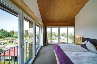 a bedroom with a bed and large windows at Hotel Landgasthof Eischen in Appenzell