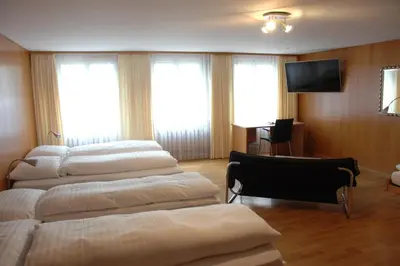 a room with four beds and a flat screen tv at Hotel Weisses Kreuz in St. Gallen