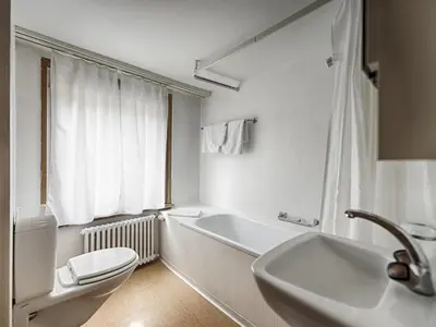 a white bathroom with a toilet and a sink at Hotel Weisses Kreuz in St. Gallen