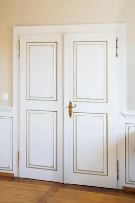 three white doors in a room with wood floors at Hotel Rotes Kreuz in Arbon