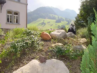 a garden with rocks and a house and a mountain at Hotel Restaurant Belvedere in Weissbad