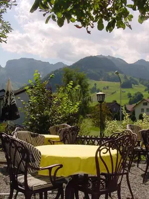 a table and chairs with a yellow table and a view of mountains at Hotel Restaurant Belvedere in Weissbad