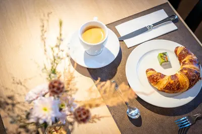 a table with a cup of coffee and a croissant at Hotel Restaurant Krone in Urnäsch