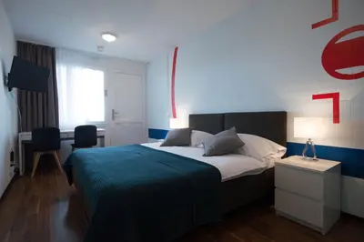 a bedroom with a large bed with a blue blanket at Hotel Bodensee-Arena in Kreuzlingen