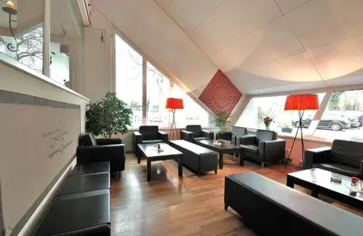 a waiting room with couches and tables and windows at Hotel Bodensee-Arena in Kreuzlingen
