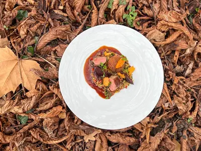 a white plate with a piece of pizza on top of leaves at Schloss Wartegg in Rorschacherberg