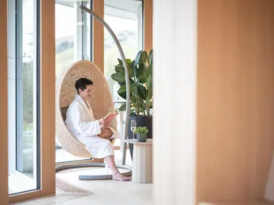 a man in a white robe sitting in a chair at Hof Weissbad Health & Wellness Resort in Weissbad