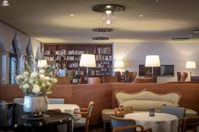 a lobby with tables and chairs and a library at Hof Weissbad Health & Wellness Resort in Weissbad