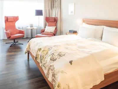 a hotel room with a bed and a chair at Hof Weissbad Health & Wellness Resort in Weissbad