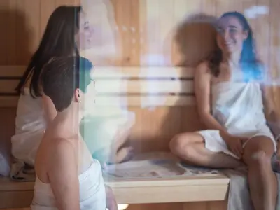 a couple of women sitting in a sauna at Hof Weissbad Health & Wellness Resort in Weissbad