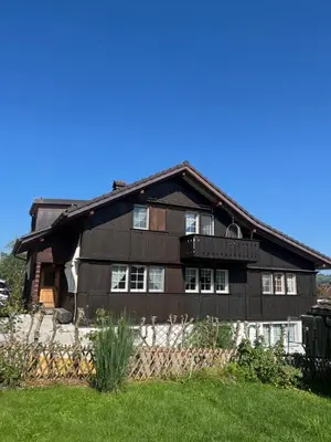 a large wooden house with a fence in front of it at Ferienwohnung Inauen in Appenzell