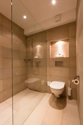 a bathroom with a toilet and a glass shower at Bären - Das Gästehaus in Gais