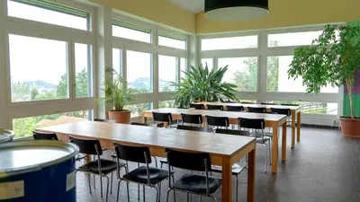 a row of tables and chairs in a room with windows at St. Gallen Youth Hostel in St. Gallen