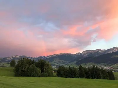 a rainbow in the sky over a green field at Ferienstudio Familie Fässler-Dörig in Appenzell