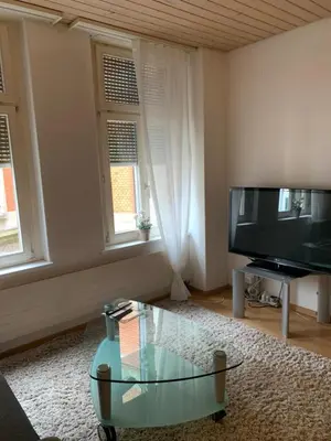 a living room with a tv and a glass coffee table at room service Joppich in St. Gallen
