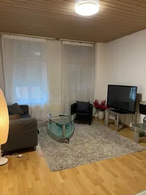 a living room with a glass table and a tv at room service Joppich in St. Gallen