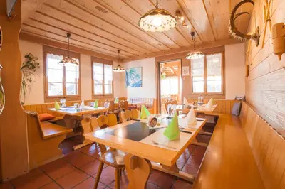 a restaurant with wooden tables and chairs and windows at Hotel Restaurant Schönau in Wildhaus